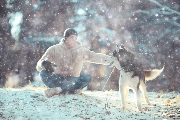 冬の森の中を犬と散歩する男晴れたクリスマスの風景公園の男と犬の自然界の友人 — ストック写真
