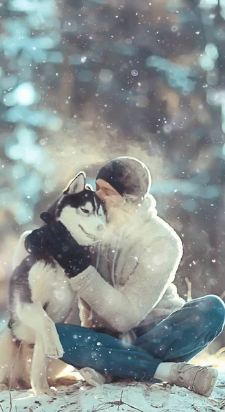 年轻人在森林里抱着一只哈士奇狗 一个男人和一只狗拥抱在一起 在冬天的自然景观中玩耍 — 图库照片