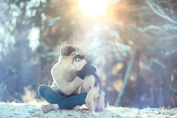 年轻人在森林里抱着一只哈士奇狗 一个男人和一只狗拥抱在一起 在冬天的自然景观中玩耍 — 图库照片