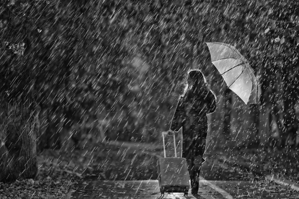 少女は秋の公園で傘とスーツケースを持って歩いている夜旅行悲しみ別れ離婚の概念 — ストック写真
