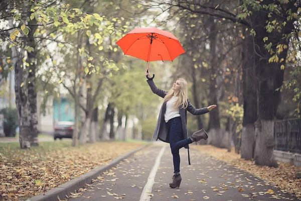 赤い傘の女の子が傘の上を飛んで飛び跳ねたり黄色の秋の風景の中で楽しんでいます — ストック写真