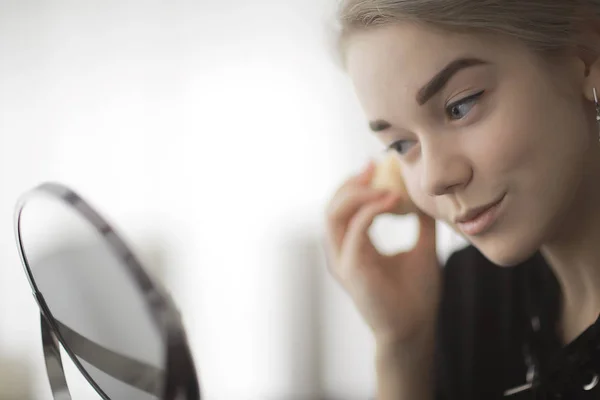 鏡によって家で化粧の女の子 若いブロンドの大人のモデル 顔化粧品の概念 — ストック写真