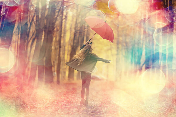 Young woman dancing in an autumn park with an umbrella, spinning and holding an umbrella, autumn walk in a yellow October park