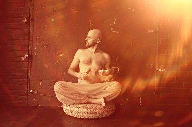 Tibet şarkı kasesi, sarı pantolonlu bir keşiş meditasyon yapar ve müzik kasesi, Budizm ve din çalar.