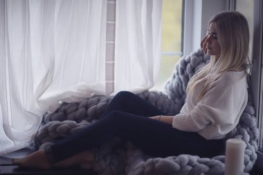 Kışın evin içinde, örnek bir kız pencerede örgü örüp güneşleniyor, evde soğuk bir gün.