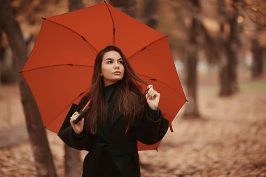 Şemsiyeli kız sonbahar parkında poz veriyor, Ekim manzaralı yalnız kadın elinde kırmızı bir şemsiye tutuyor.