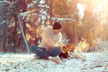 young man hugs a husky dog in the winter in the forest, a man and a dog hug together and play in a winter nature landscape
