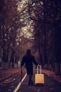 Sonbahar akşamında kadın şemsiyesini tutuyor, Ekim ayında, karanlık şehir parkında, şemsiyeli genç yalnız model.