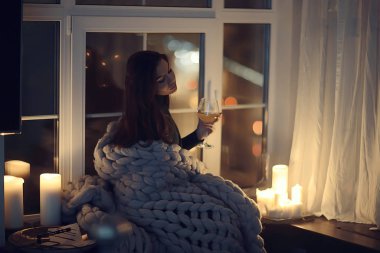 Pencerenin önünde battaniyede oturan kız, mumlar gece, yalnızlık, genç yalnız kız, stres