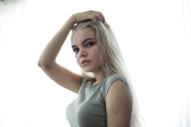 Genç, sarışın, uzun saçlı, şık bir model stüdyoda poz veriyor.