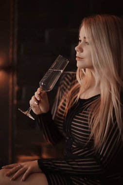 Seksi sarışın kız kadehten şampanya içiyor. Akşam gösterişli bir portreden.