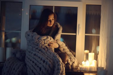 Ev cana yakın kız ekose pencere, ev sonbaharı görünümü, sıcak örgü örülmüş battaniyenin içindeki model ısınıyor.