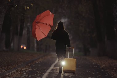 Kız elinde şemsiyeyle sonbahar parkında yürüyor. Seyahat, üzüntü, ayrılık, boşanma kavramı.
