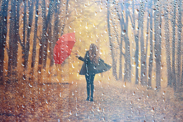 Autumn rain woman, beautiful model in the rain in a city park, autumn warm tones, yellow leaves, autumn weather concept