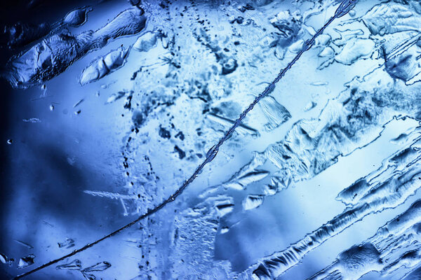 Blue ice glass background, abstract texture of the surface of the ice on the glass, frozen seasonal water