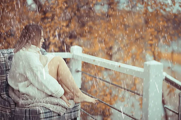 girl with a book in autumn rain on the veranda of the house, seasonal portrait romantic autumn with rain, weather raindrops