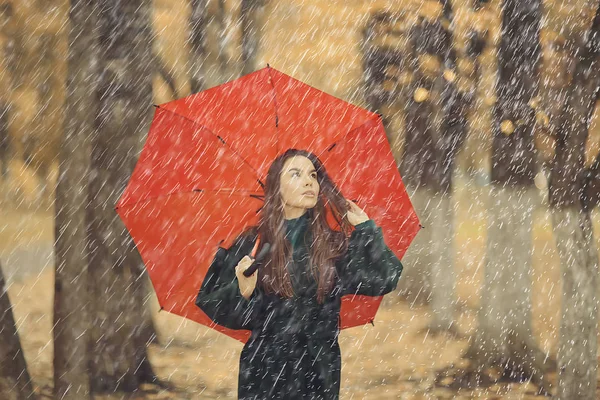 October walk in the rain, a young woman with a red umbrella in the autumn city park, autumn look