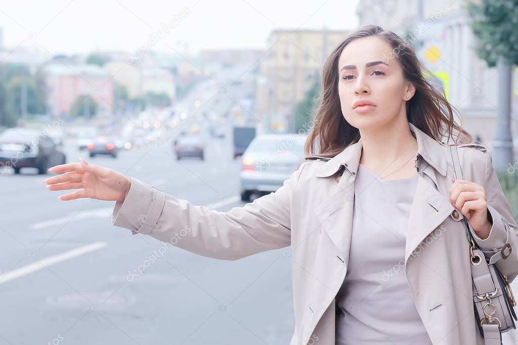 woman catches a car on the road, an adult young girl is waiting for a taxi, stops a passing vehicle, hitchhiking
