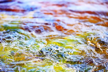 Su akışının çok renkli dokusu, temiz su, nehrin dibindeki renkli taşlar.