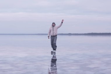 Bir adam donmuş bir gölün buzunda kayıyor, doğa manzarası, açık hava sporları.