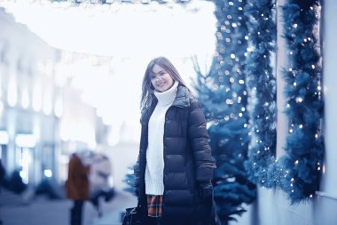 Kız Noel ışıkları akşam dekore edilmiş şehir, şehir dekorasyonları ve çelenklerin arka planında genç bir model, gece şehir ışıkları