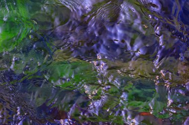 Su akışının çok renkli dokusu, temiz su, nehrin dibindeki renkli taşlar.