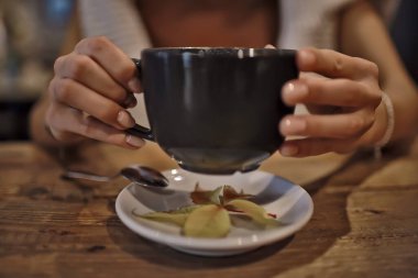 Bir kafede elinde bir fincan kapuçino, restoranın içinde bir kahve.