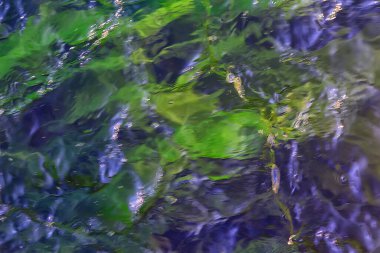 Su akışının çok renkli dokusu, temiz su, nehrin dibindeki renkli taşlar.