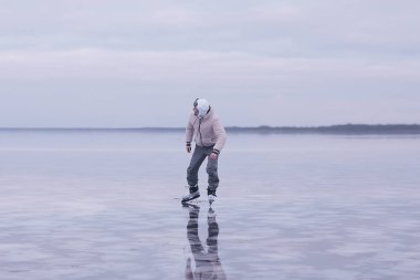 Bir adam donmuş bir gölün buzunda kayıyor, doğa manzarası, açık hava sporları.
