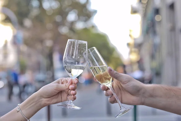 glasses of toast chin chin, hands with glasses of white wine in a street cafe