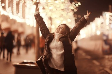 Kız Noel ışıkları akşam dekore edilmiş şehir, şehir dekorasyonları ve çelenklerin arka planında genç bir model, gece şehir ışıkları