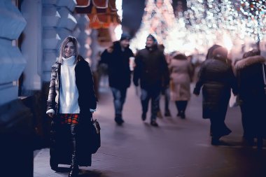 Kız Noel ışıkları akşam dekore edilmiş şehir, şehir dekorasyonları ve çelenklerin arka planında genç bir model, gece şehir ışıkları