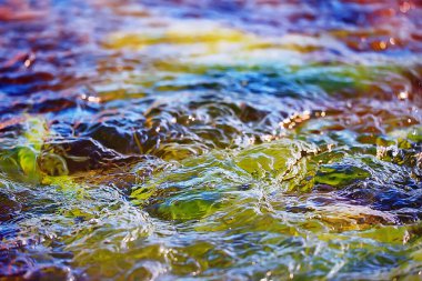 Su akışının çok renkli dokusu, temiz su, nehrin dibindeki renkli taşlar.