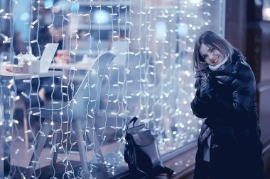 Kız Noel ışıkları akşam dekore edilmiş şehir, şehir dekorasyonları ve çelenklerin arka planında genç bir model, gece şehir ışıkları