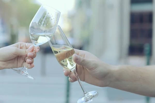 glasses of toast chin chin, hands with glasses of white wine in a street cafe