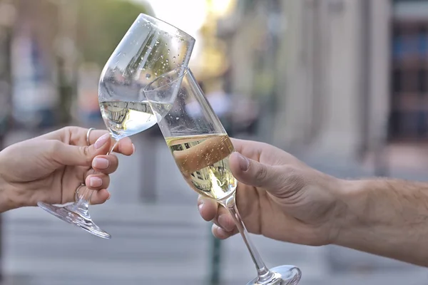 glasses of toast chin chin, hands with glasses of white wine in a street cafe