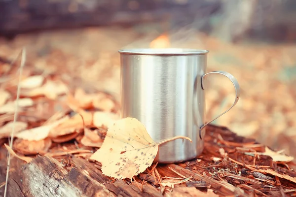 iron mug with hot tea on a camping trip active lifestyle autumn yellow park