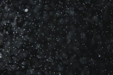 soyut arkaplan, siyah üzerine beyaz bokeh düşen kar sisi görünümünü örtüyor