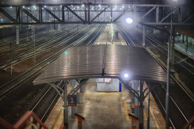 Demiryolu, sonbaharda tren istasyonundaki gece manzarasını izler.