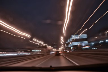 Gece şehrinin soyut görüntüsü bir araba penceresinden bulanık, şehirde trafik...