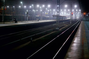 Demiryolu, sonbaharda tren istasyonundaki gece manzarasını izler.