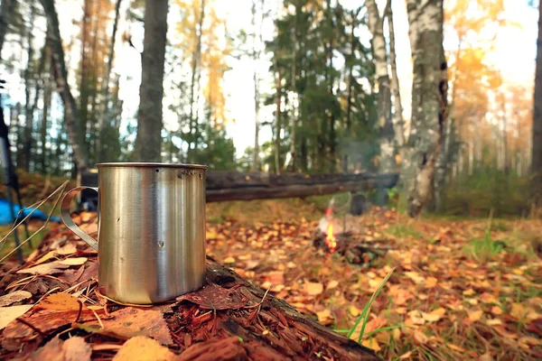 Demir kupa ve sıcak çay. Kamp gezisinde aktif yaşam tarzı. Sonbahar sarı parkı.
