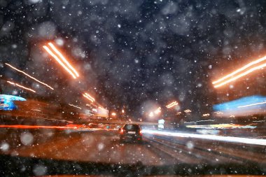 Gece şehrinin soyut görüntüsü bir araba penceresinden bulanık, şehirde trafik...