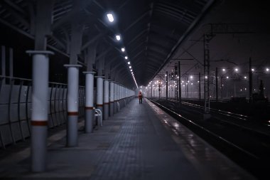 Demiryolu, sonbaharda tren istasyonundaki gece manzarasını izler.