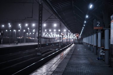 Demiryolu, sonbaharda tren istasyonundaki gece manzarasını izler.