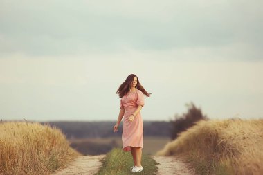 Yazın genç esmer, tarlada uzun saçlı, gün batımında poz veren mutlu insan sağlığı güzeli.