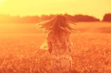 Yazın genç esmer, tarlada uzun saçlı, gün batımında poz veren mutlu insan sağlığı güzeli.