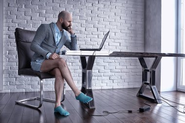 Pantolonu olmayan bir adam bilgisayarda, laptopta, mizah koronavirüsünde külot içinde çalışıyor.