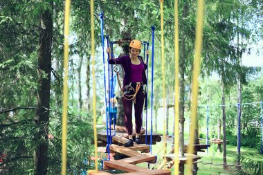 Aşırı tatil, sarı başlıklı halat parkındaki kız ormanda aktif tatiller.