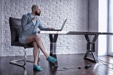 Pantolonu olmayan bir adam bilgisayarda, laptopta, mizah koronavirüsünde külot içinde çalışıyor.